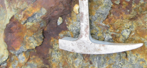 Rusty rock coating with hammer for scale